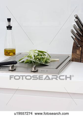 Picture - Close-up of sliced vegetables with knife on stainless steel hob. Fotosearch