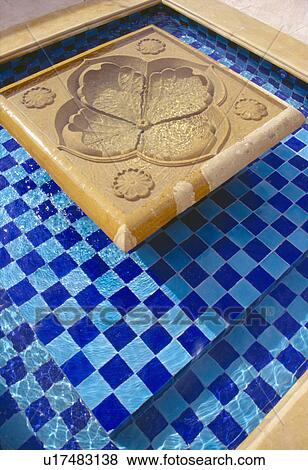Stock Photo - Close-up of small blue tiled pool with flower shaped marble fountain. Fotosearch