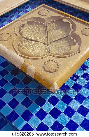 Stock Photography - Close-up of small blue tiled pool with flower shaped marble fountain. Fotosearch