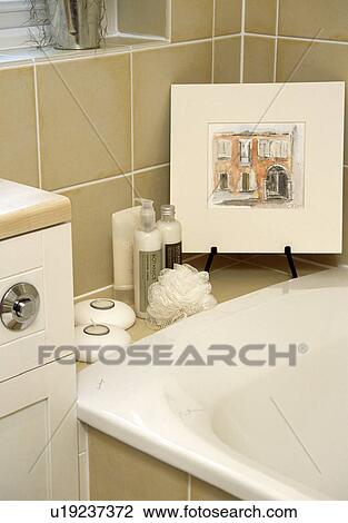Stock Image - Close up of small picture and toiletries on side of bath. Fotosearch