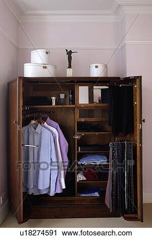 Stock Image - Close-up of small wardrobe with doors open showing men's clothing. Fotosearch