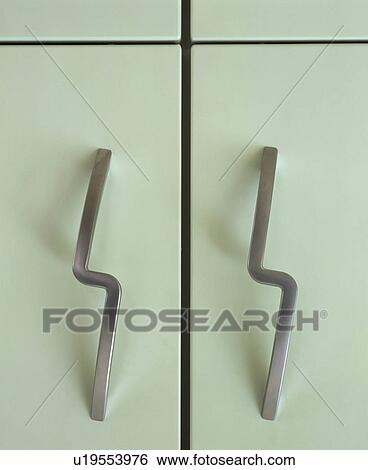 Stock Photograph - Close-up of stainless steel handles on white storage cupboard. Fotosearch