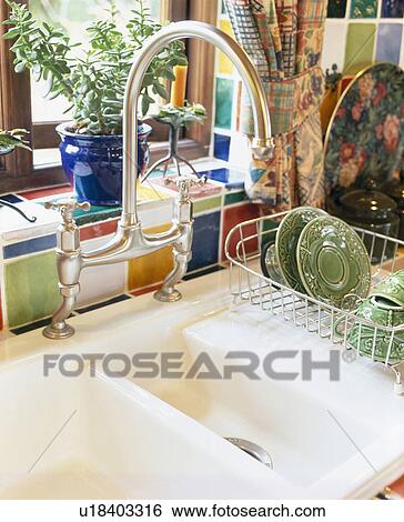 Close-up of stainless steel mixer tap and double white ceramic sink with metal draining basket on draining board View Large Photo Image Stock Photograph - Close-up of stainless steel mixer tap and double white ceramic sink with metal draining basket on draining board. Fotosearch