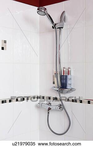 Stock Photography - Close-up of stainless steel shower-head in white tiled shower. Fotosearch