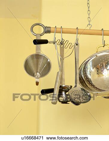 Stock Image - Close-up of stainless steel utensils and colander on storage pole. Fotosearch