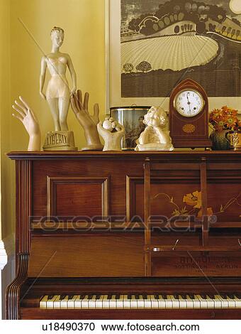 Stock Image - Close-up of statues and small antique clock on piano. Fotosearch
