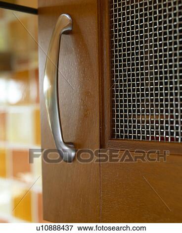 Stock Photo - Close-up of steel handle and mesh panel on walnut door. Fotosearch
