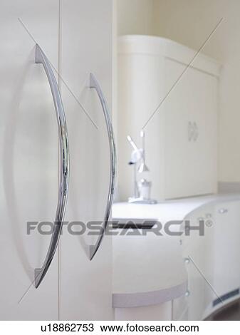 Stock Image - Close-up of steel handles on white kitchen cupboard. Fotosearch