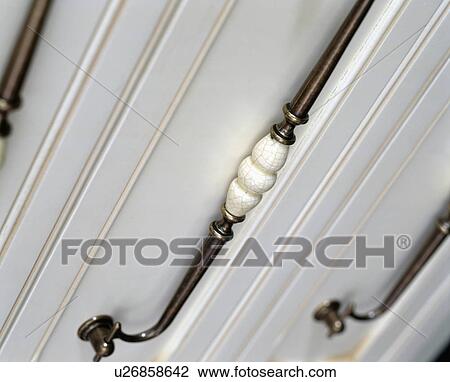 Stock Image - Close-up of steel handles on white cupboard. Fotosearch