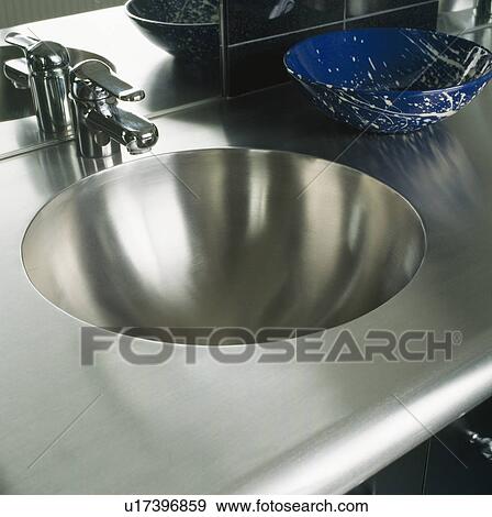 Stock Photo - Close-up of steel tap and circular steel sink and worktop. Fotosearch