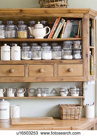 Stock Image - Close-up of storage jars on fitted pine wall cupboard with drawers. Fotosearch