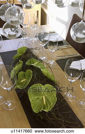 Stock Image - Close-up of table with wineglasses and green leaves in table decoration. Fotosearch