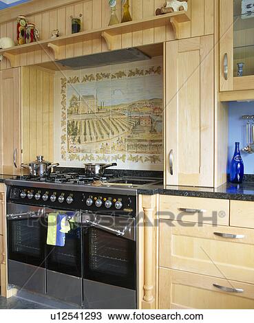 Stock Image - Close-up of tiled picture above range oven. Fotosearch