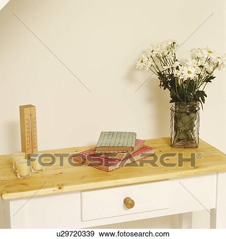 Stock Photo - Close-up of vase of white daisies on small wooden table with books and candles . Fotosearch