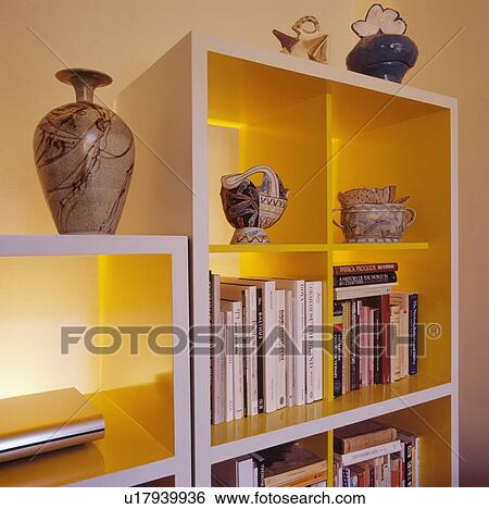 Stock Photograph - Close-up of vases and books on modern white shelves. Fotosearch