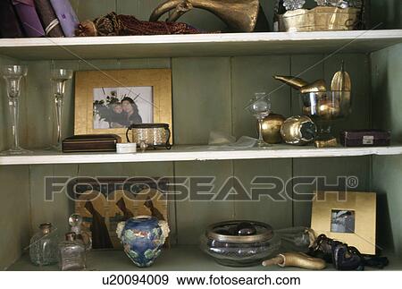 Stock Photo - Close-up of vases and gold framed pictures on shelves. Fotosearch