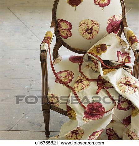 Stock Image - Close-up of viola patterned cream fabric on matching upholstered chair. Fotosearch