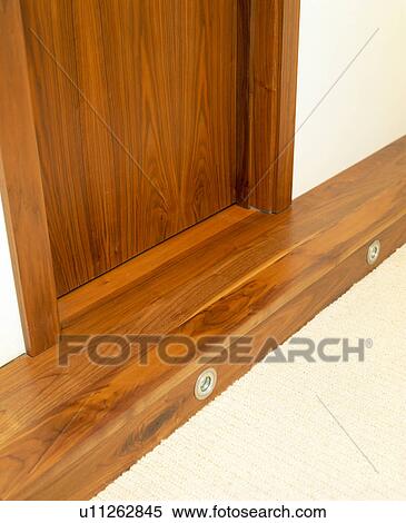 Stock Photography - Close-up of walnut door and skirting-board with integral lighting. Fotosearch