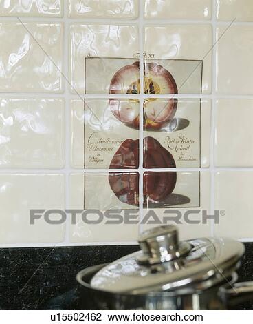 Stock Image - Close-up of white ceramic tiled wall with inset tiled picture of apples. Fotosearch