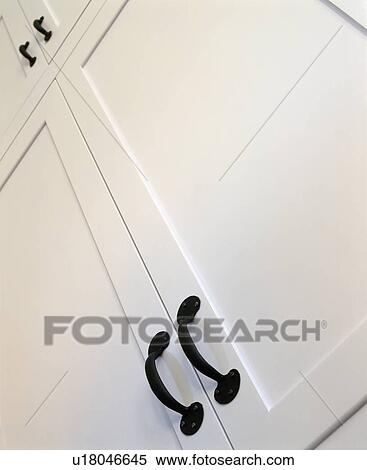 Stock Photography - Close-up of white cupboard doors with black metal handles. Fotosearch