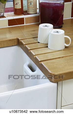 Close Up Of White Cups On Wooden Draining Board Beside White Belfast Sink Stock Image