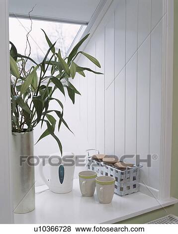 Close up of white kettles with cups and storage jars on attic windowsill with green leaves in vase View Large Photo Image Stock Photo - Close up of white kettles with cups and storage jars on attic windowsill with green leaves in vase. Fotosearch