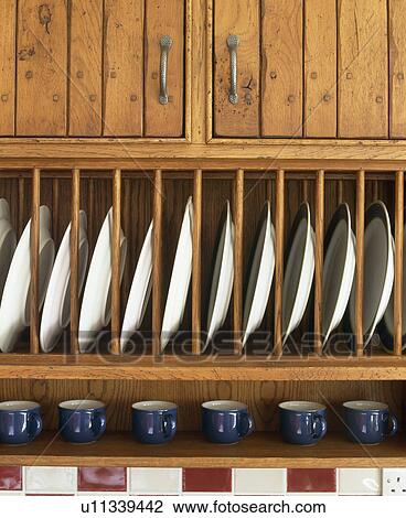Stock Image - Close-up of white plates on oak plate rack. Fotosearch