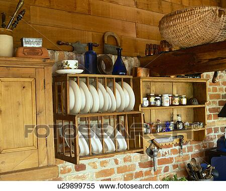 Stock Photography - Close-up of white plates on plate rack in cottage kitchen with wooden shelves. Fotosearch