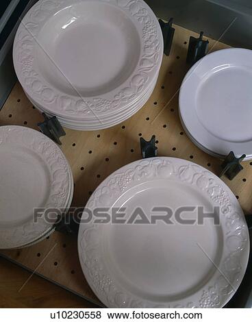 Stock Photo - Close-up of white pottery plates on plate warmer. Fotosearch