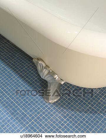 Picture - Close up of white rolltop bath with steel clawfeet on blue mosaic tiled floor. Fotosearch