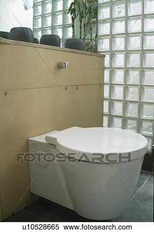Stock Photography - Close-up of white toilet beside glass brick wall. Fotosearch