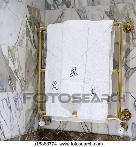 Picture - Close-up of white towels on heated brass towel rail . Fotosearch