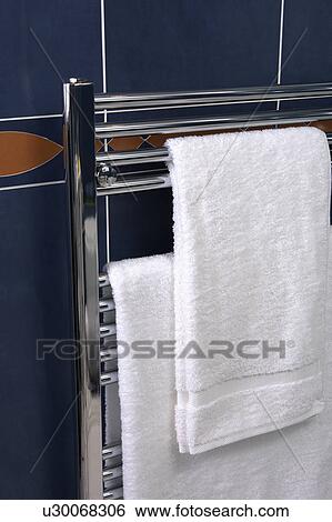 Stock Photograph - Close-up of white towels on stainless steel heated towel rail. Fotosearch