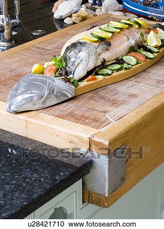Stock Image - Close-up of whole poached salmon on large salmon-shaped platter. Fotosearch