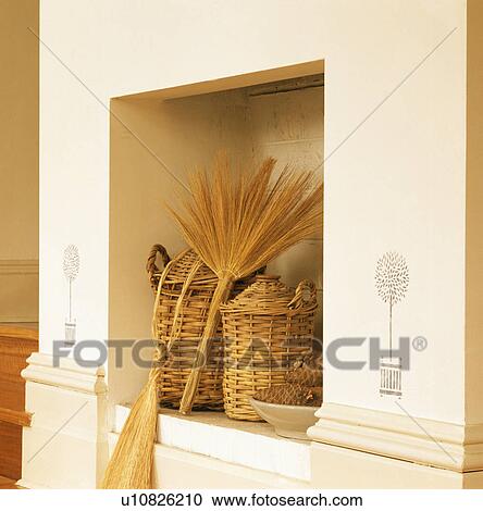 Stock Image - Close-up of wicker bottles in alcove with stencilling. Fotosearch