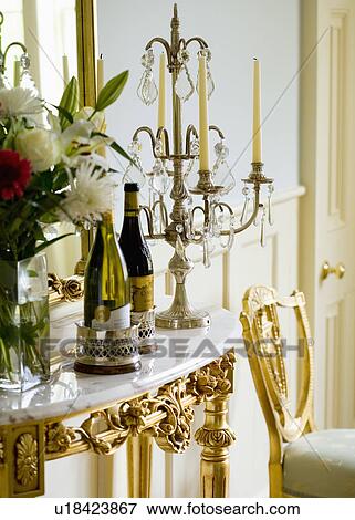 Stock Photo - Close-up of wine bottles and ornate candelabra on marble-topped gilt table. Fotosearch