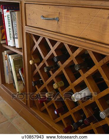 Stock Image - Close-up of wine bottles stored in wine-rack in fitted unit. Fotosearch