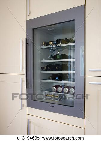 Stock Photography - Close-up of wine-cooler in modern white kitchen unit. Fotosearch