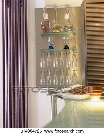 Stock Photography - Close-up of wine glasses and decanters on glass shelves beside vertical radiator. Fotosearch