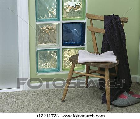 Stock Image - Close-up of wooden chair and coloured glass brick wall. Fotosearch