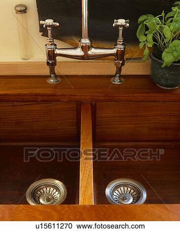 Stock Image - Close-up of wooden double sink with chrome mixer tap. Fotosearch