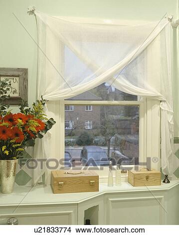Picture - Close up of wooden storage boxes below bathroom window with white voile curtains and view of outside. Fotosearch