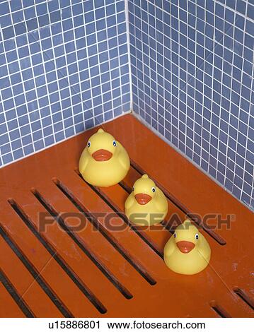 Stock Image - Close-up of yellow plastic ducks on slatted red floor. Fotosearch