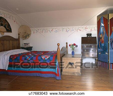 Colourful patchwork quilt on bed in traditional bedroom with pine chest and wooden flooring View Large Photo Image Stock Image - Colourful patchwork quilt on bed in traditional bedroom with pine chest and wooden flooring. Fotosearch