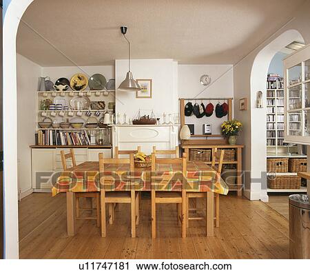 Stock Image - Colourful plastic cloth on table in white dining room with wooden flooring. Fotosearch