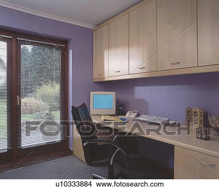 Computer on fitted desk below storage units in modern purple home office View Large Photo Image Picture - Computer on fitted desk below storage units in modern purple home office. Fotosearch