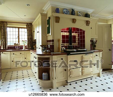 Stock Photograph - Cream Aga double oven in large townhouse kitchen with black+white ceramic tiled floor. Fotosearch
