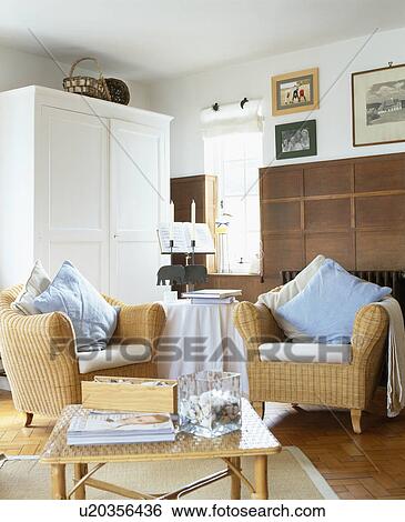 Cream and pastel blue cushions on wicker armchairs in living room with large white cupboard View Large Photo Image Stock Photograph - Cream and pastel blue cushions on wicker armchairs in living room with large white cupboard. Fotosearch