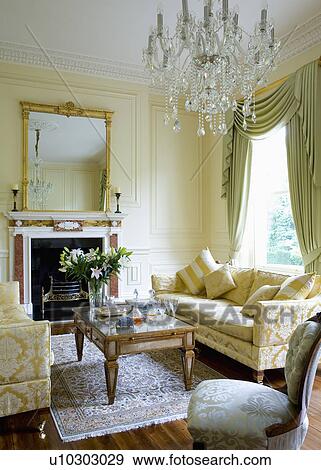 Cream brocade sofas and glass-topped coffee table in cream panelled drawing room with glass chandelier View Large Photo Image Stock Photo - Cream brocade sofas and glass-topped coffee table in cream panelled drawing room with glass chandelier. Fotosearch