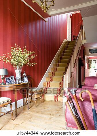 Picture - Cream carpet with red edging on staircase in hall with red wallpaper and wooden flooring. Fotosearch
